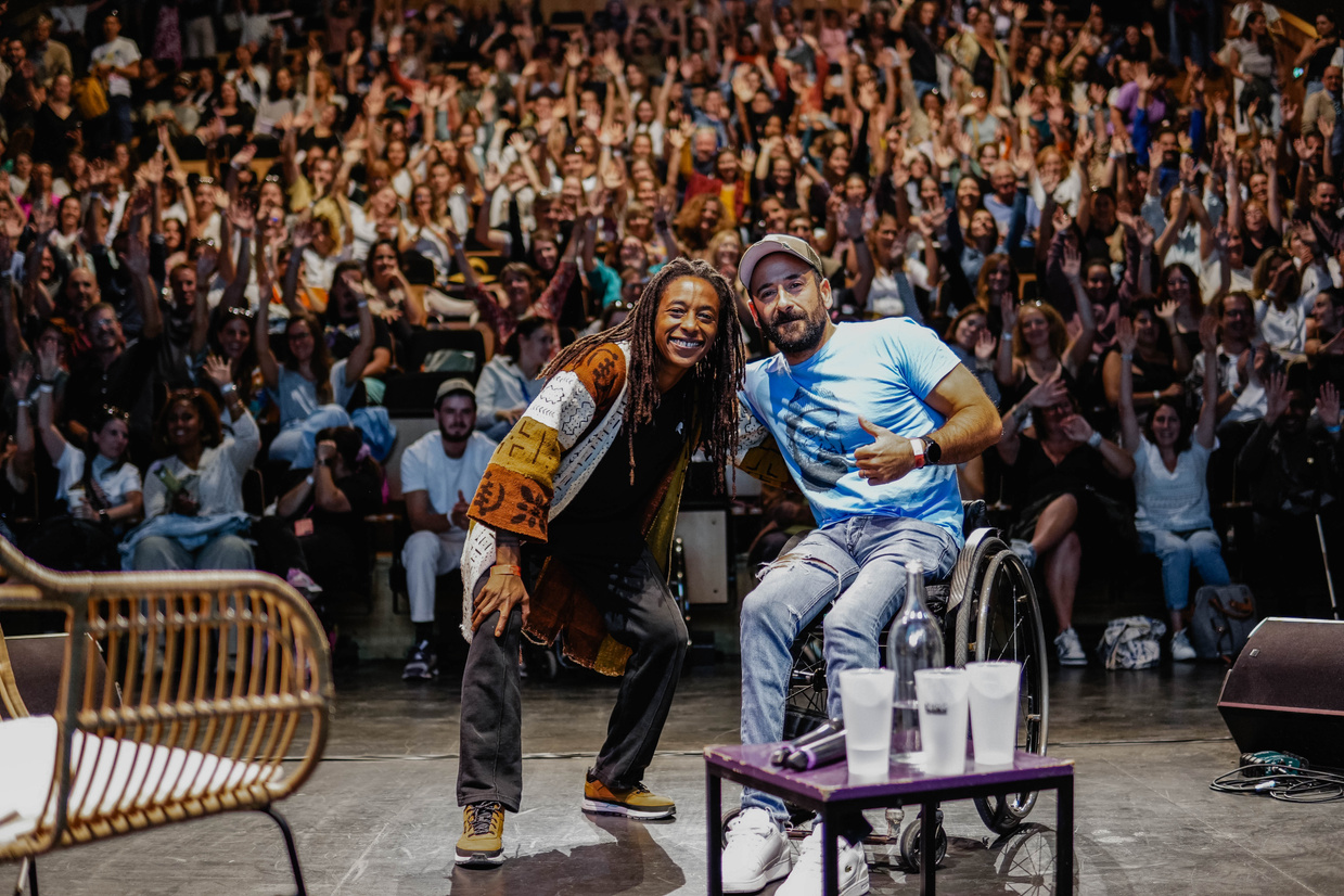 Deux intervenant·es en pleine conférence sur scène, devant une salle comble et enthousiaste.